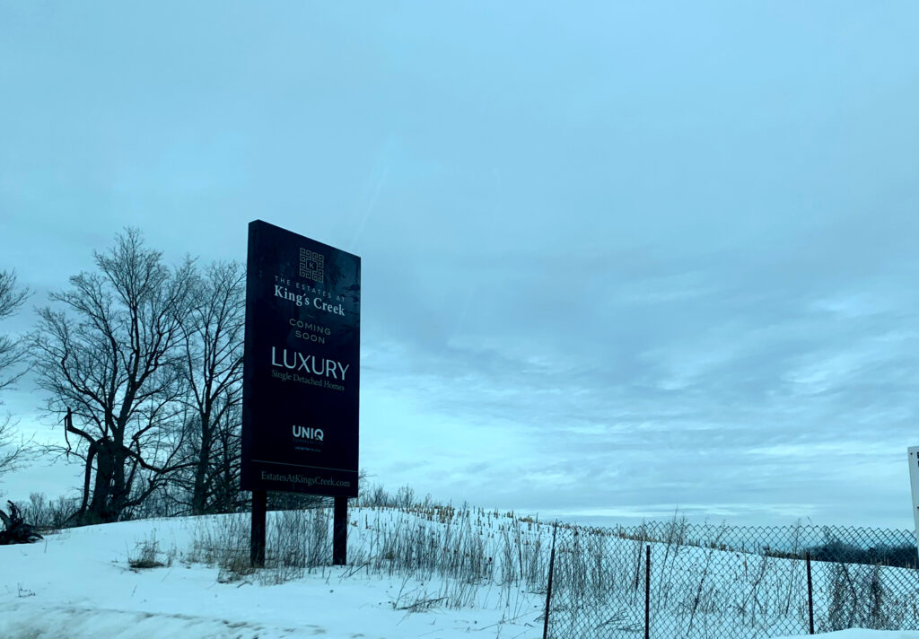 Black King's Creek Homes sign pitched against white snow hill