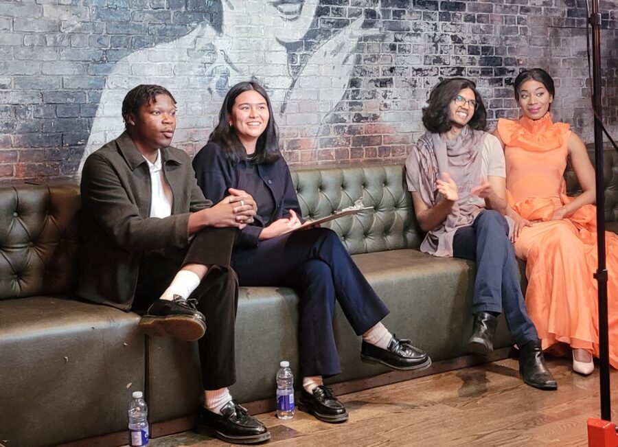 4 people sit on a large couch talking to a camera out of frame