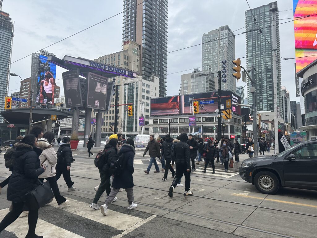 People crossing through the busy intersection of Yonge and Dundas.